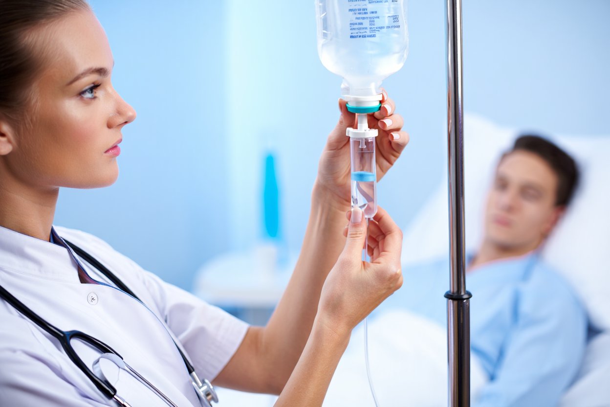 Медсестра настраивает капельницу пациенту в палате